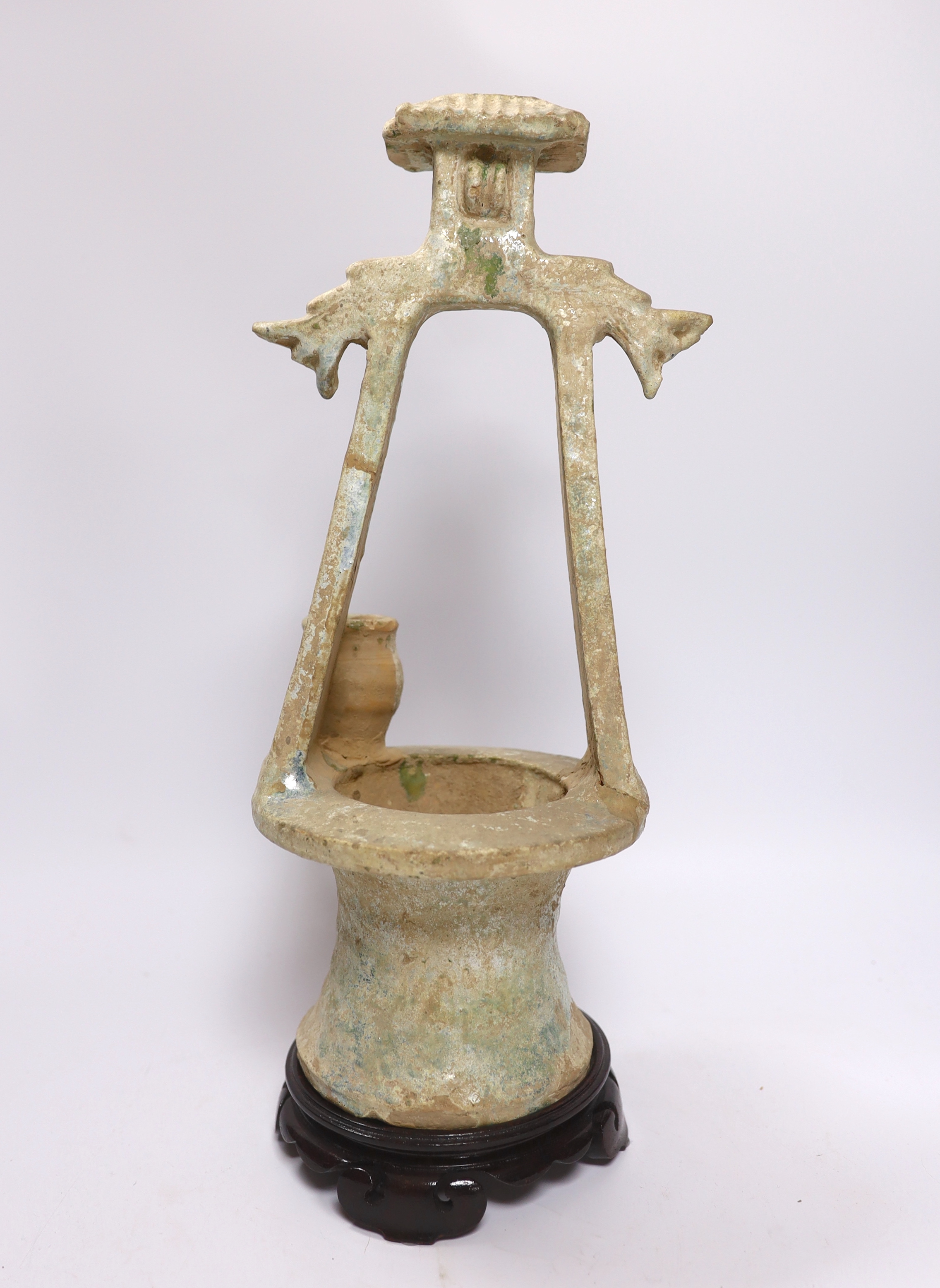 A Chinese glazed pottery model of a well, Han dynasty, with mineral iridescence, stand, 37cm high